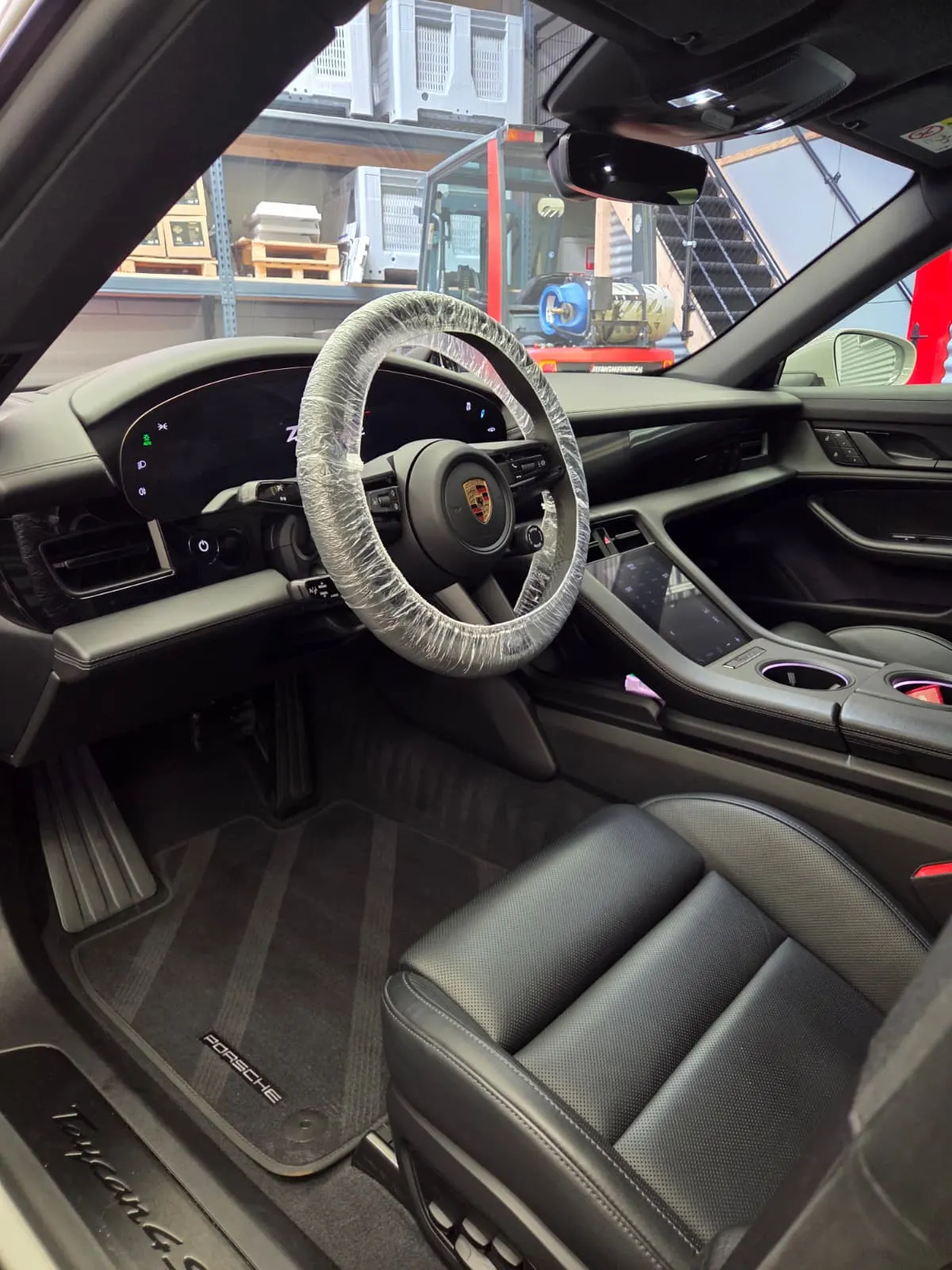 Interieur van een Porsche Taycan, met een beschermhoes om het stuur